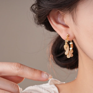 Close-up of golden geometric twisted earrings featuring unique metallic woven textures