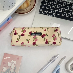 Detailed macro of vintage floral corduroy pouch with zipper and brand label on a desk