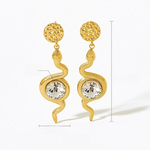 Detailed view of golden snake-shaped earrings with textured scales and round glass beads