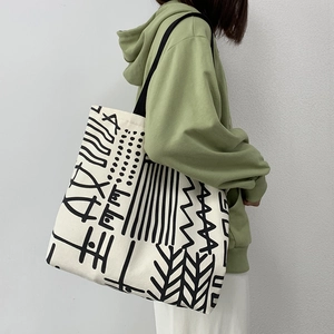 Dettaglio della grande borsa tote in tela con motivi geometrici astratti neri e tracolla