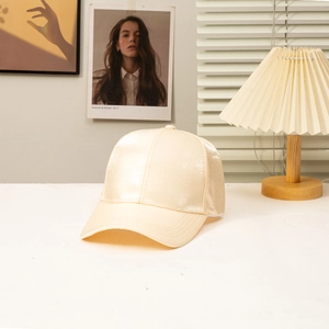 Detailed close-up of champagne satin baseball cap with smooth silky texture and fine stitching