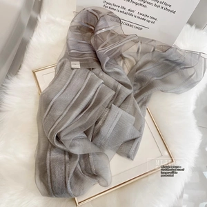 Detail of grey silk wool scarf with metallic gold stripes and translucent texture