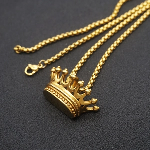 Macro shot of gold-plated crown pendant on stainless steel chain with a textured black background