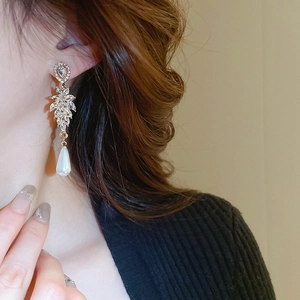Detailed close-up of long drop earrings with marquise leaves and water-drop pearl on model