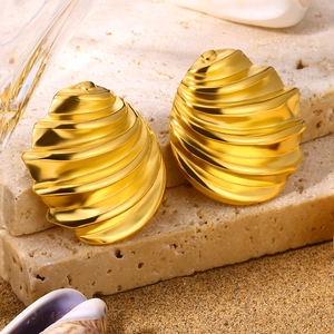Golden shell-shaped textured stud earrings set on a beach sand background