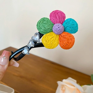 Détail d'une barrette à fleurs en raphia coloré et cœurs en cristal sur pince noire