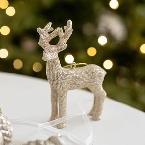 Décoration de renne pailleté or champagne suspendue au sapin de Noël avec lumières chaudes