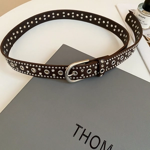 Detailed macro view of vintage brown leather belt with silver eyelets and rhinestones
