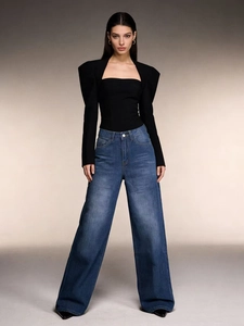 Detail of high waisted wide leg blue jeans styled with a slim fit black long sleeve top