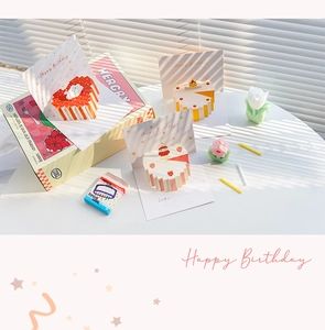 Dettaglio di biglietti d'auguri 3D pop-up con torte e scatola regalo di lusso