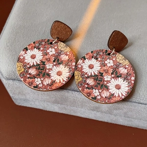 Close-up of vintage round earrings with floral pattern and dark wood triangular studs