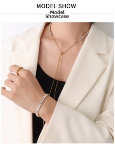 Modella indossa collana con nappa dorata, bracciale in zirconi e anello con blazer