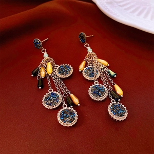 Détail de boucles d'oreilles vintage avec pierres bleues et glands perlés colorés