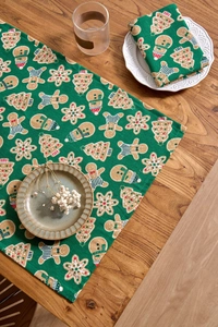 Close-up of green gingerbread man printed cloth napkin and table runner set