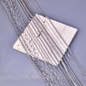 Detailed view of various silver stainless steel Cuban and link chains on stone base