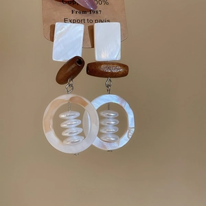 Detail of bohemian shell and wooden bead drop earrings with natural textures