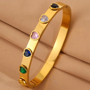 Bracelet cœur en or avec zircons multicolores, vue macro sur un fond en tissu plissé