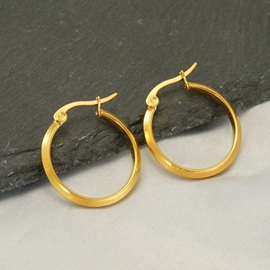 Classic 18k gold-plated stainless steel hoop earrings on minimalist stone and fabric background