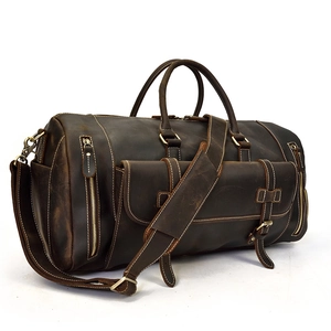Macro detail of dark brown leather travel bag with brass hardware and side zipper pocket