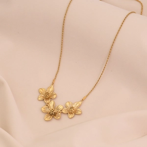 Vue macro détaillée des pendentifs fleur dorés sur un collier chaîne torsadée