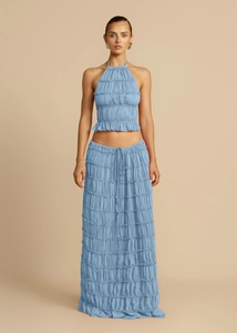 Detail of light blue pleated two-piece set featuring a halter crop top and long maxi skirt