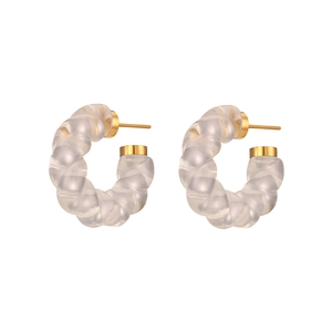 Boucles d'oreilles créoles torsadées en acrylique avec accents dorés sur fond blanc