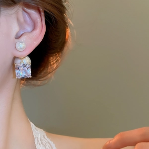 Detail shot of pearl earrings with square zirconia pendant and gold plated finish