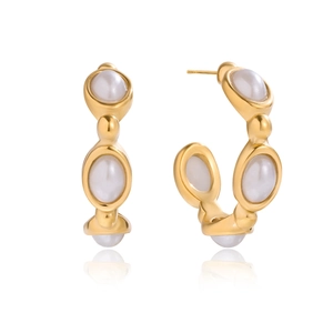 Macro detail of gold-plated C-shaped hoop earrings featuring inlaid white resin pearls