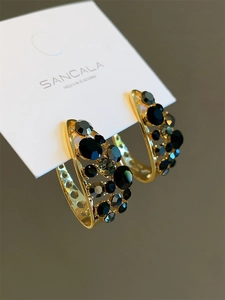 Vue macro des boucles d'oreilles C vintage dorées serties de zircons noirs et gris
