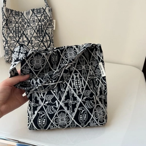 Close-up of intricate black and white embroidery patterns on vintage canvas tote bag