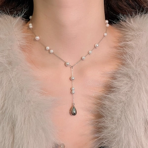 Détail d'un élégant collier en Y avec chaîne argentée, petites perles et pendentif