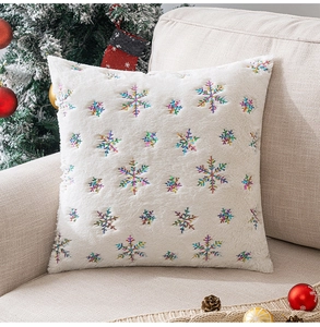 Detail of white plush Christmas pillow cover with colorful sequin snowflake embroidery