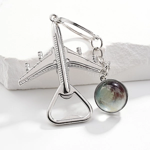 Macro detail of silver plane keychain with glass globe and integrated bottle opener