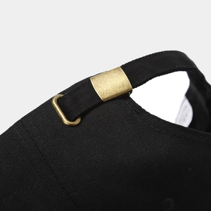 Detail of black baseball cap showing the vintage brass metal buckle and adjustable strap