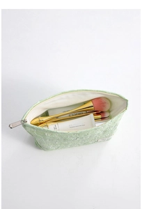 Detail of light green floral lace cosmetic bag with silver zipper and textured fabric