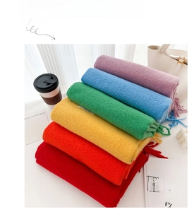 Stack of vibrant soft solid color scarves with fringed edges in a lifestyle setting.