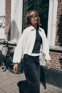 Détail d'une veste courte blanche à fermeture éclair et col à revers pour l'automne
