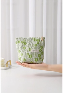 Close-up of floral jacquard makeup bag with gold zipper and flower pendant detail
