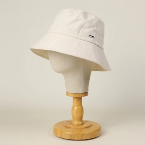 Detail of cream cotton bucket hat with plaid stitching and small silver metal tag