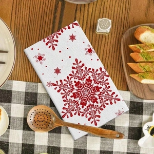 Detail of microfibre kitchen towel with red snowflake pattern on a rustic wooden table