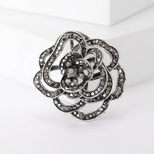Elegant silver spider lily brooch with dark grey rhinestones on a white pedestal
