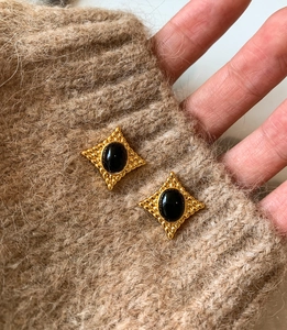 Vue macro de boucles d'oreilles vintage avec pierre noire sur fond en maille marron