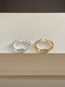 Macro detail of silver and gold fish rings with zircon pavé and link chain band