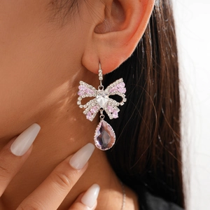 Close-up of pink zircon bow earrings with teardrop crystal pendant on female model