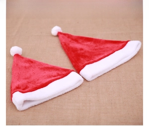 Flat lay of red and white plush Santa hats on a rustic linen background with soft texture