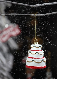 Detailed view of resin three-layer Christmas cake ornament with red and gold glitter accents