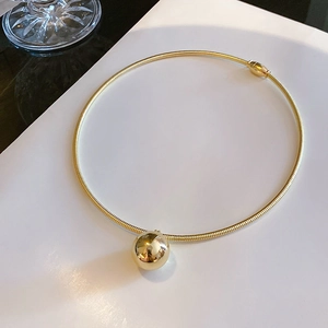 Close-up of a minimalist gold ball choker necklace with a high-polish mirror finish