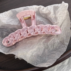 Close-up of pink chain-link hair claw clip with marble texture on white paper