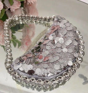 Detailed view of silver sequin crescent evening bag with rhinestone handle on mirror