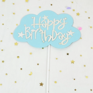 Macro shot of light blue cloud cake topper with Happy Birthday text and gold star sequins